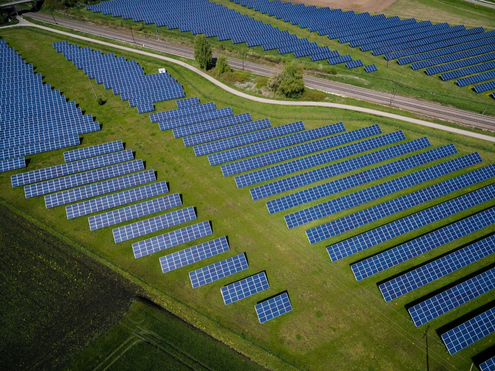 Aerial view of rows of solar panels in a green field